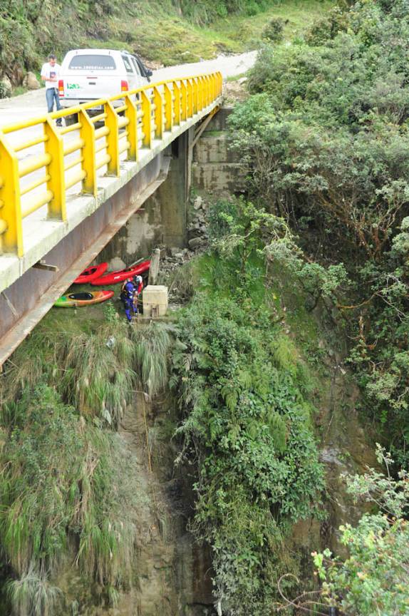 Fiona atravessa ponte sobre desfiladeiro enquanto, embaixo, pessoas descem seus caiaques de rapel para navegar no rio lá embaixo (na estrada entre Popayan e San Agustín, na Colômbia